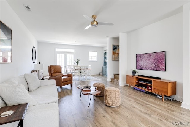 living area featuring baseboards, ceiling fan, light wood-type flooring, and visible vents