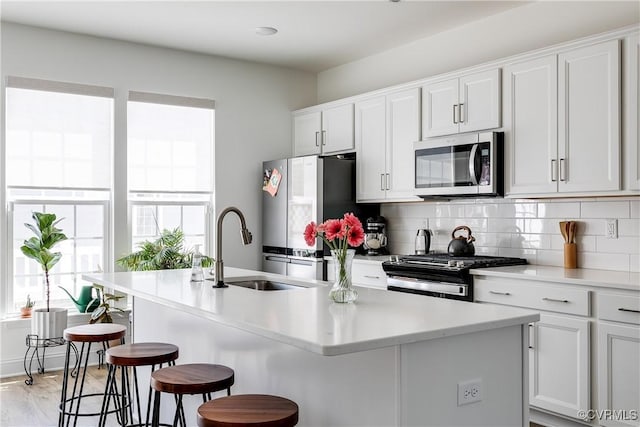 kitchen with a sink, appliances with stainless steel finishes, plenty of natural light, and a breakfast bar area