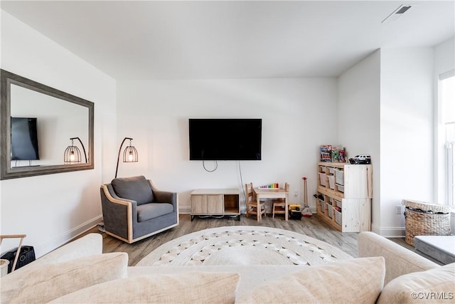 living area with baseboards, wood finished floors, and visible vents