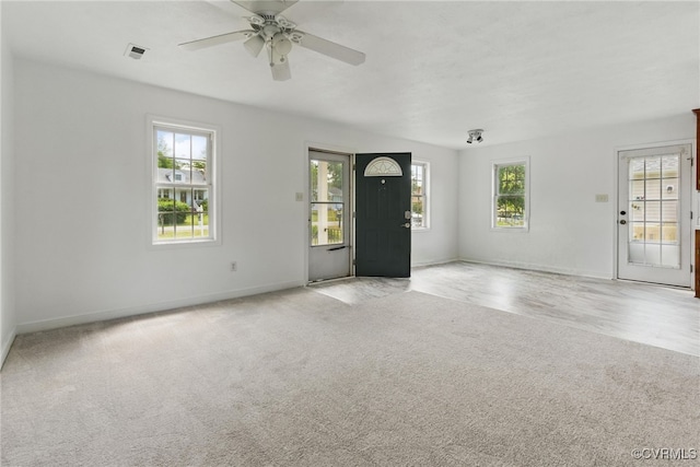unfurnished living room with light colored carpet, baseboards, and ceiling fan