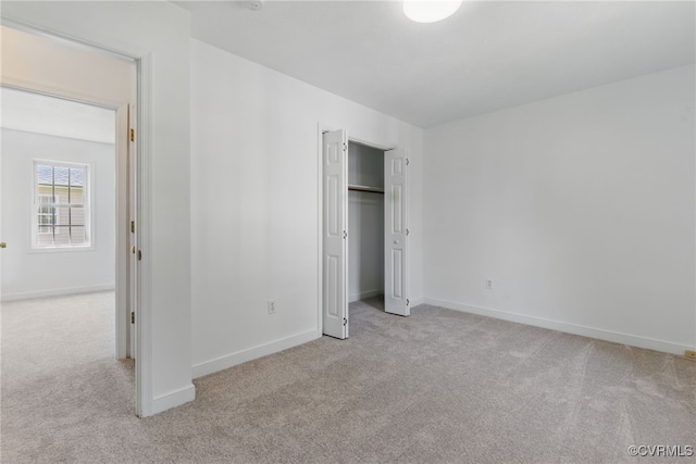 unfurnished bedroom featuring light colored carpet, baseboards, and a closet