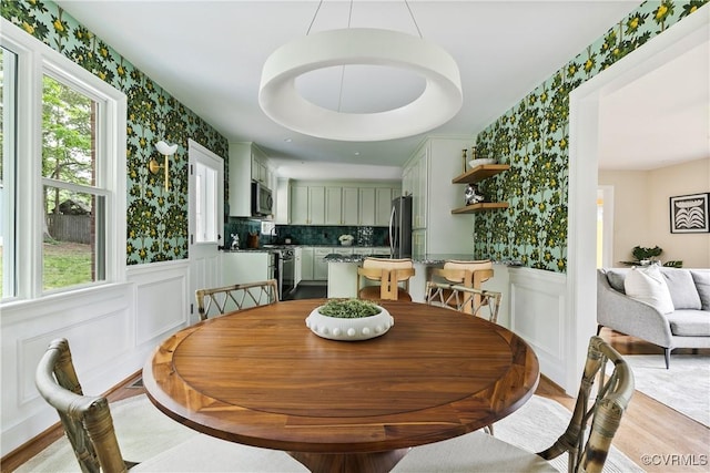 3454 Warner Rd, Richmond, VA 23225 - dining area featuring wallpapered walls, plenty of natural light, light wood-style flooring, wainscoting, and a decorative wall