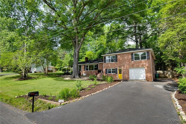 3454 Warner Rd, Richmond, VA 23225 - tri-level home with driveway, a chimney, a garage, view of scattered trees, and brick siding