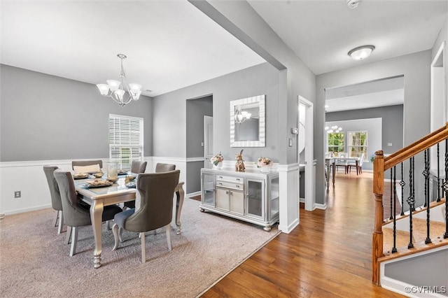 dining room featuring an inviting chandelier, baseboards, stairs, and wood finished floors