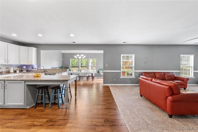 living room with an inviting chandelier, baseboards, recessed lighting, and wood finished floors