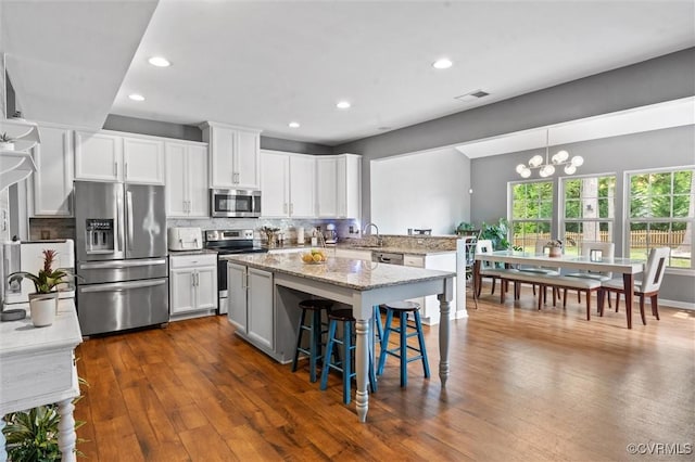 kitchen with dark wood-style flooring, an inviting chandelier, stainless steel appliances, recessed lighting, and backsplash
