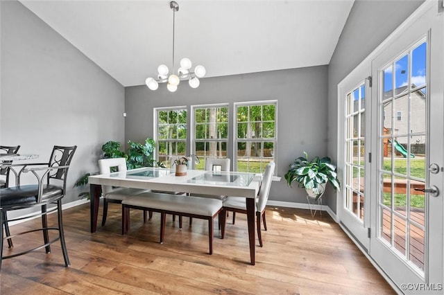 dining space featuring baseboards, vaulted ceiling, light wood-style flooring, and an inviting chandelier