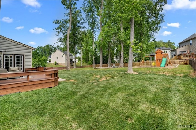 view of yard featuring a deck, fence, and a playground