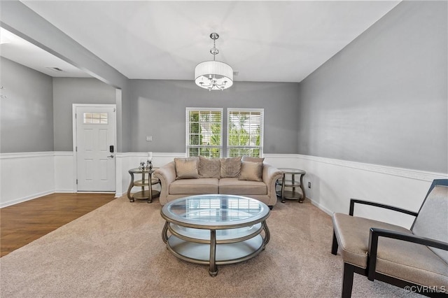 carpeted living area featuring a chandelier, wainscoting, and visible vents