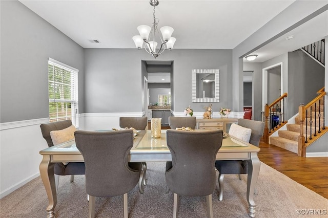 dining space with visible vents, carpet floors, baseboards, a notable chandelier, and stairs