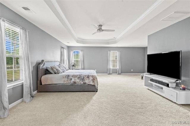 carpeted bedroom featuring a ceiling fan, visible vents, a raised ceiling, baseboards, and ornamental molding