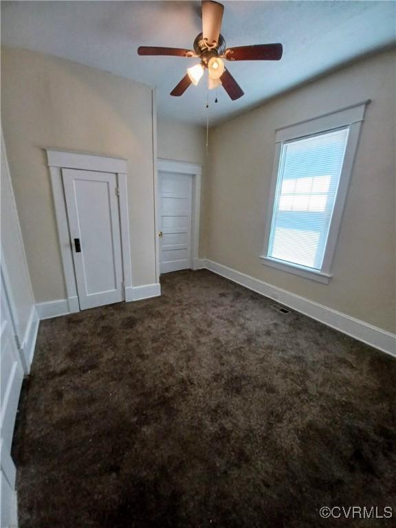 130 Elm St, Petersburg, VA 23803 - unfurnished bedroom with dark colored carpet, baseboards, and ceiling fan