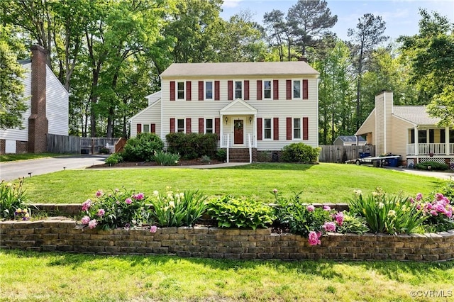 colonial-style house featuring fence and a front yard