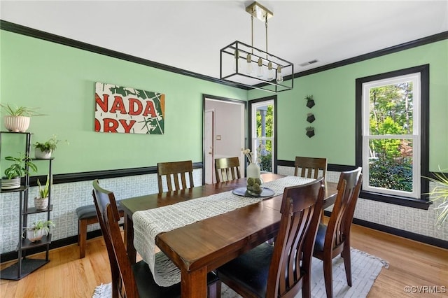 dining area featuring crown molding, light wood finished floors, and a healthy amount of sunlight