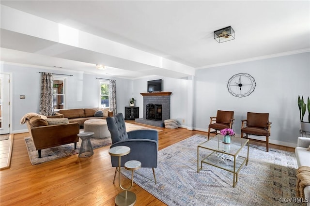 living room featuring baseboards, ornamental molding, a brick fireplace, and wood finished floors