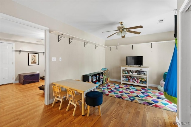 recreation room featuring baseboards, ceiling fan, wood finished floors, and visible vents
