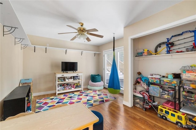 rec room with baseboards, a ceiling fan, and wood finished floors