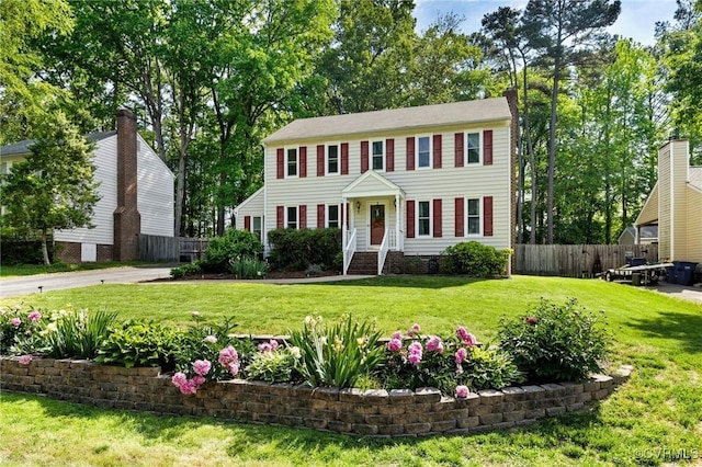 colonial-style house with a front lawn and fence