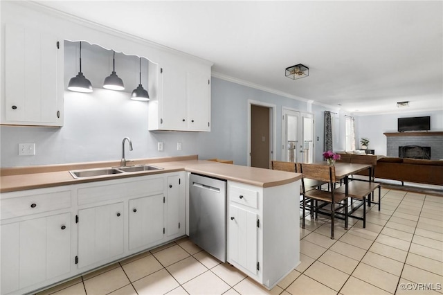 kitchen featuring a sink, dishwasher, a brick fireplace, a peninsula, and light tile patterned floors