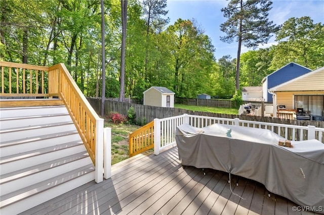 wooden deck with a storage unit, a fenced backyard, stairs, and an outbuilding