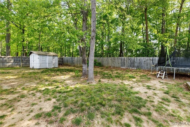 view of yard featuring an outdoor structure, a fenced backyard, a trampoline, and a storage unit