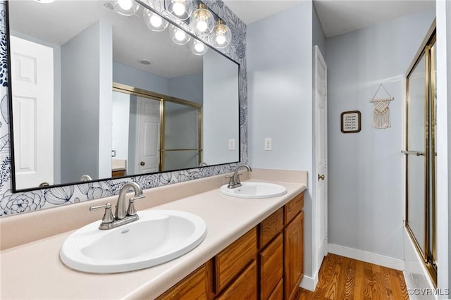 bathroom with an enclosed shower, a sink, and wood finished floors