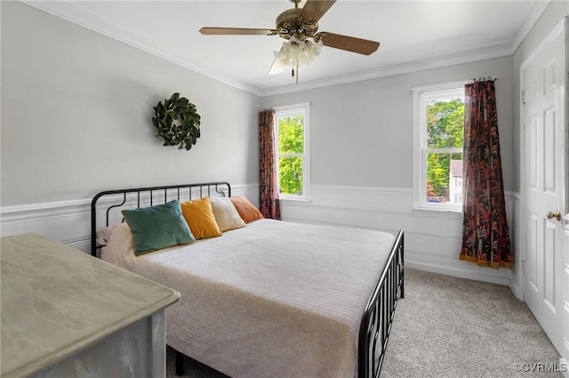 carpeted bedroom featuring crown molding, multiple windows, and a wainscoted wall