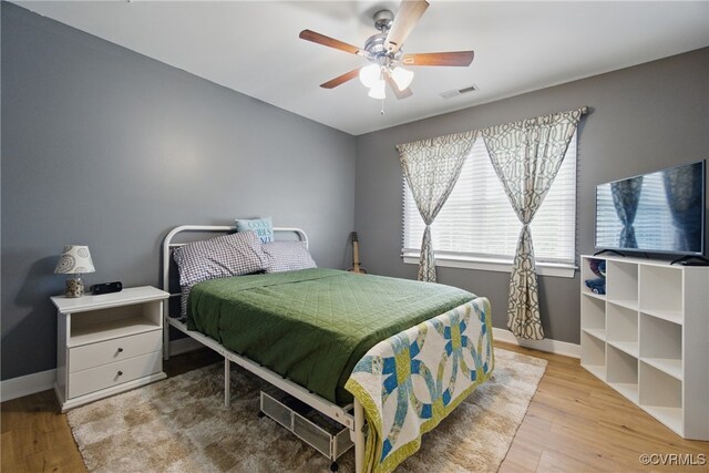 bedroom featuring ceiling fan, baseboards, visible vents, and wood finished floors