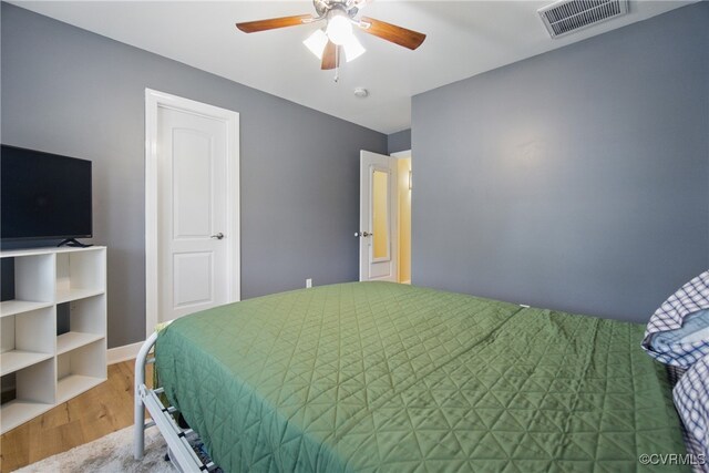 bedroom featuring a ceiling fan, baseboards, visible vents, and wood finished floors