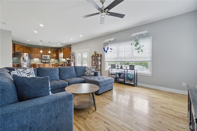 living room with a ceiling fan, baseboards, recessed lighting, and light wood-style floors