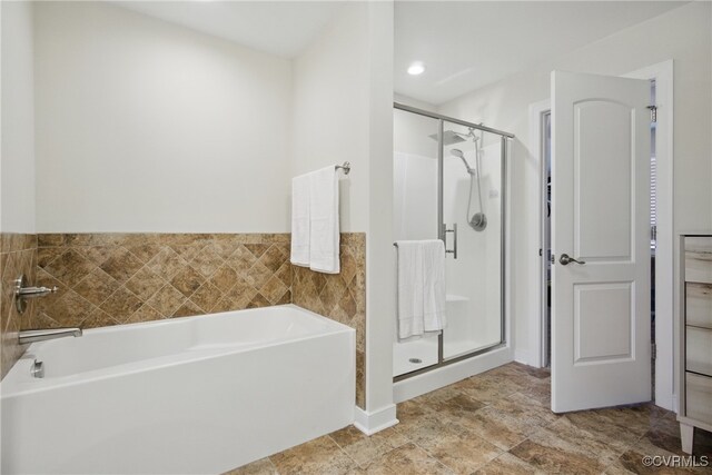 bathroom featuring a stall shower and a bath