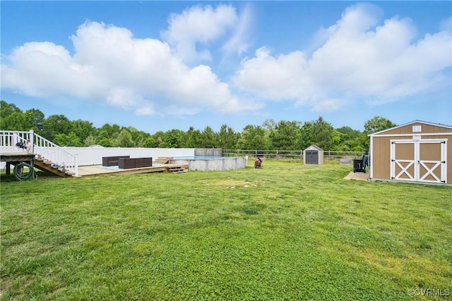 view of yard featuring a deck, an outbuilding, a fenced in pool, a shed, and a fenced backyard
