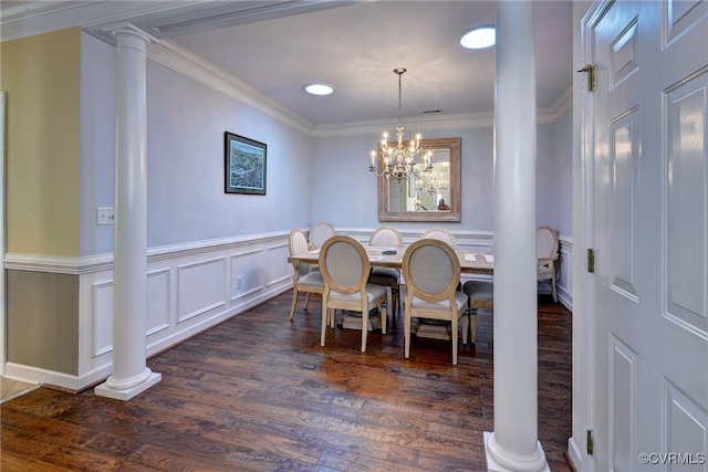dining room featuring wainscoting, a decorative wall, dark wood-type flooring, ornate columns, and ornamental molding