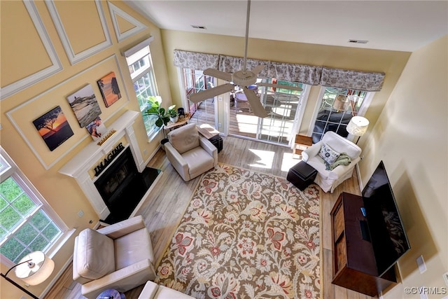 living room featuring a fireplace with raised hearth, wood finished floors, and visible vents