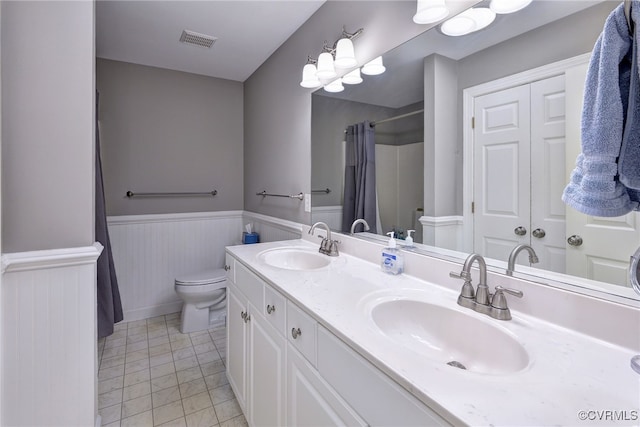bathroom featuring a sink, wainscoting, toilet, and visible vents