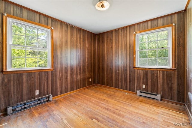 unfurnished room with wood finished floors, a baseboard heating unit, a wealth of natural light, and baseboard heating