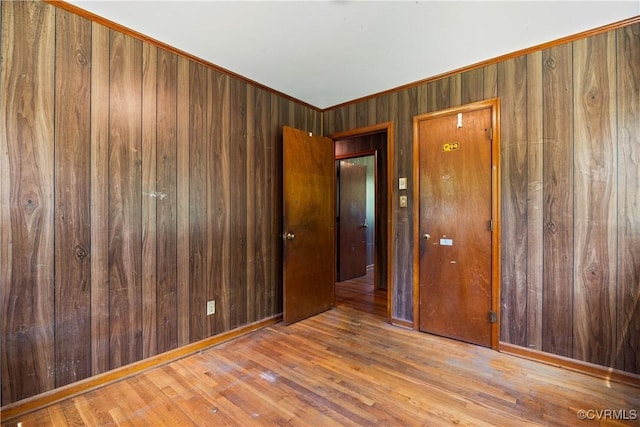 spare room featuring wooden walls, crown molding, and wood finished floors