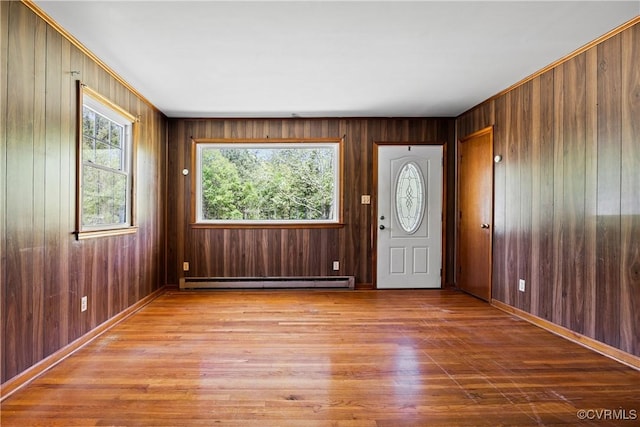 entrance foyer with wood walls, a baseboard heating unit, and wood finished floors