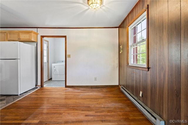 interior space with washer / dryer, a baseboard radiator, ornamental molding, and wood finished floors