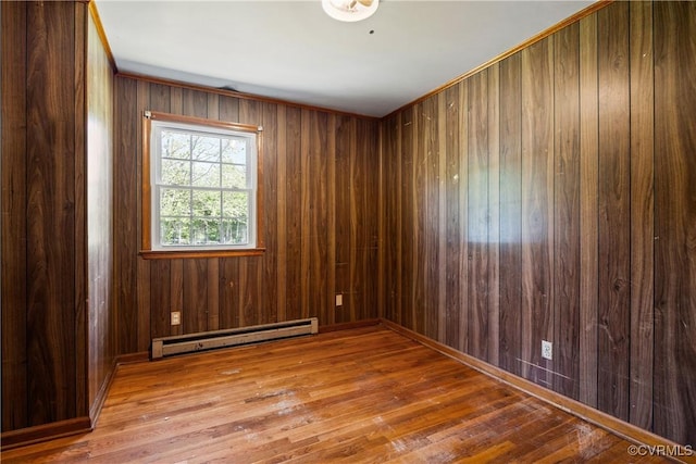 spare room featuring wooden walls, baseboard heating, and hardwood / wood-style floors