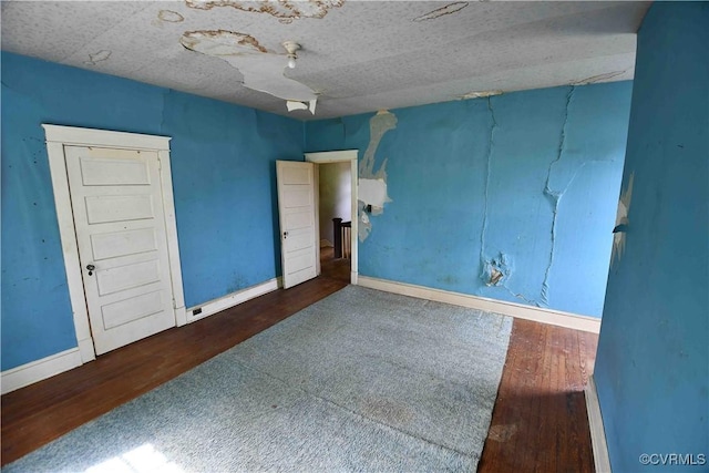 spare room with baseboards and wood finished floors