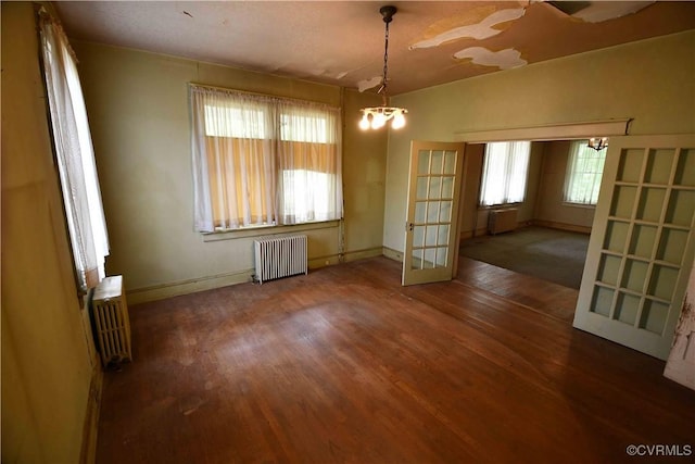 unfurnished dining area with plenty of natural light, radiator, and wood finished floors