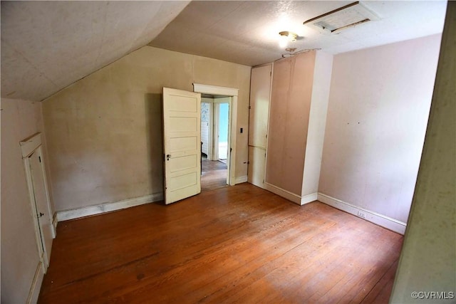 interior space with baseboards, vaulted ceiling, and wood finished floors