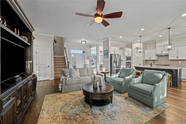 living room featuring crown molding, ceiling fan, dark wood-type flooring, stairs, and recessed lighting