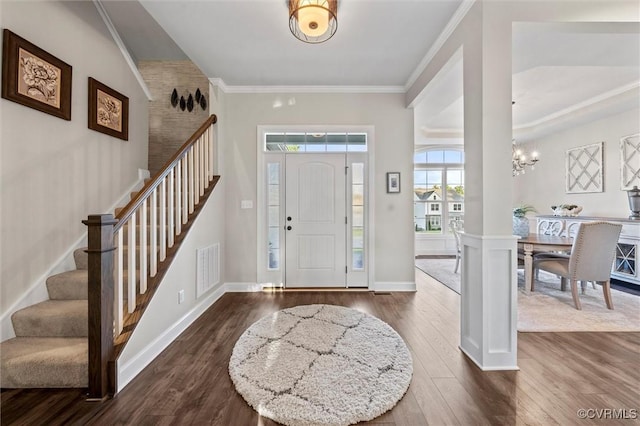 foyer entrance featuring stairs, dark wood-style flooring, a chandelier, crown molding, and baseboards