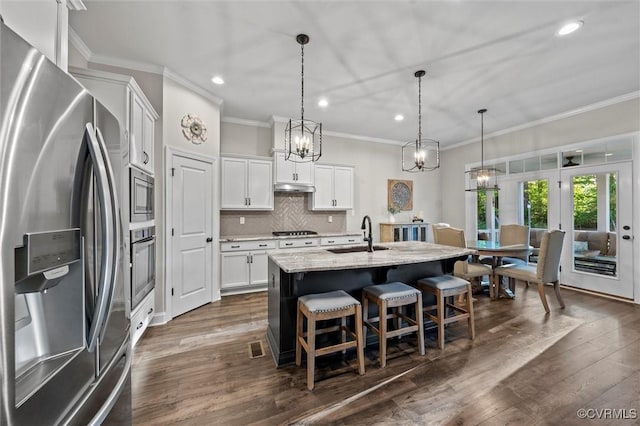 kitchen with stainless steel appliances, a sink, ornamental molding, recessed lighting, and a breakfast bar area