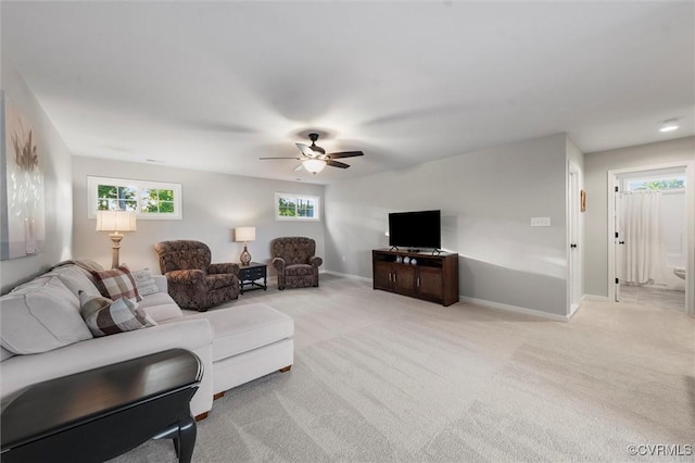 living room featuring light colored carpet, a ceiling fan, and baseboards