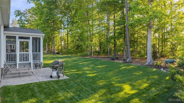 view of green lawn featuring a sunroom and a patio area