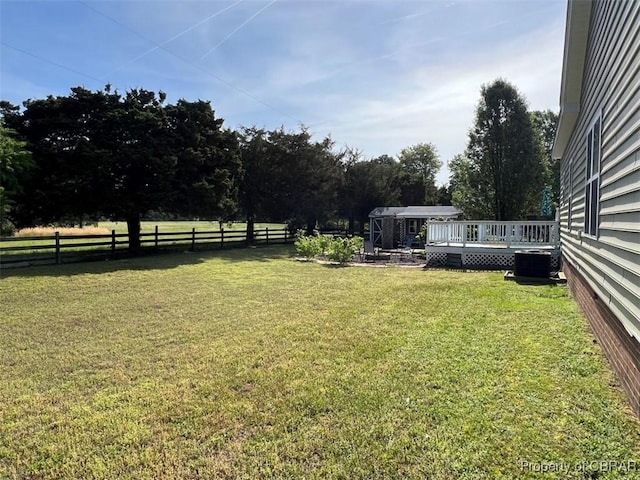 view of yard featuring fence, a wooden deck, and central AC unit