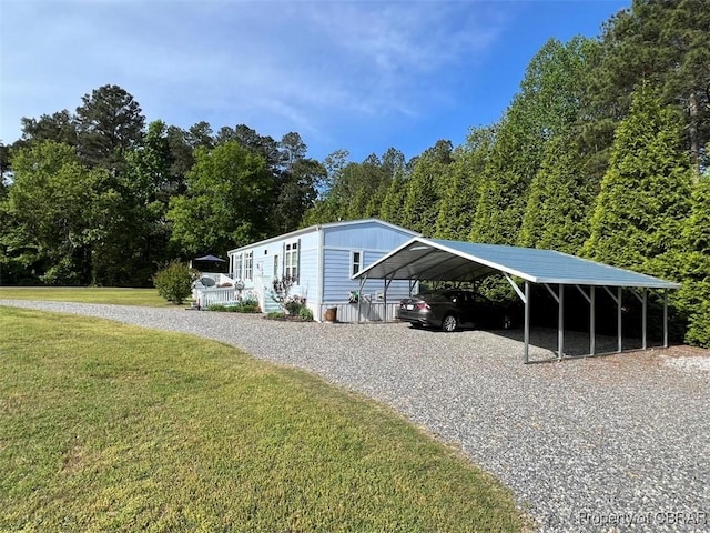 exterior space with a wooded view, a detached carport, and gravel driveway